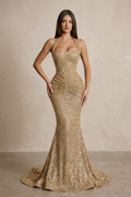 Woman wearing a gold sequin evening gown against a neutral background
