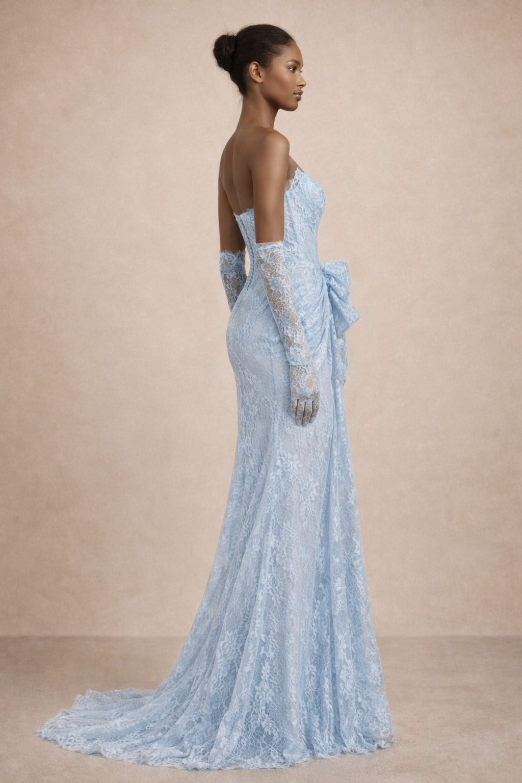 Woman wearing a light blue lace evening gown with a beige background