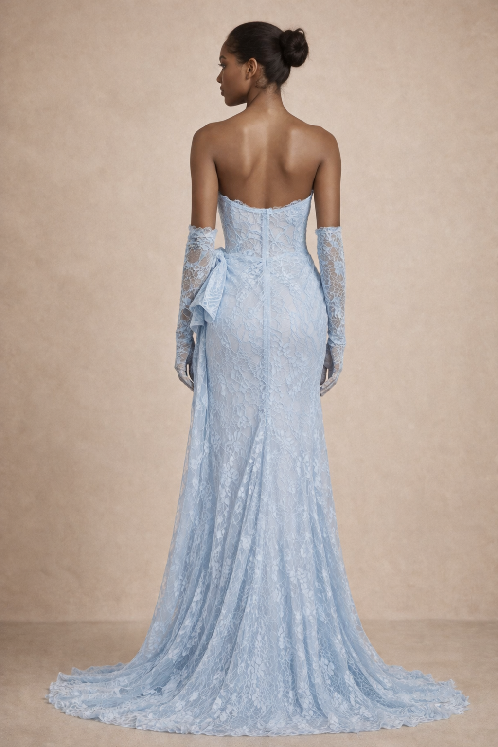 Woman wearing a light blue strapless gown with lace detailing on a beige background